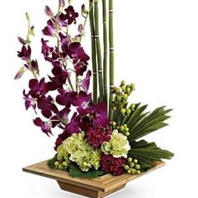 Tall orchid arrangement with bamboo and green hydrangeas in a wooden base