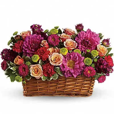 Mixed pink and purple flowers arranged in a wicker basket
