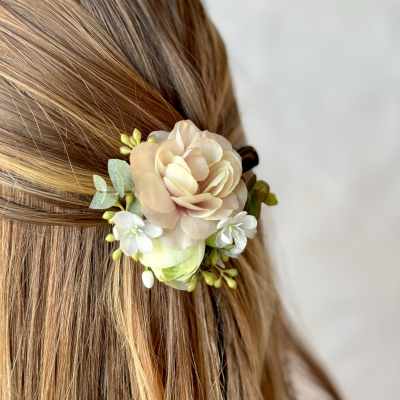 Floral hair accessory with pale peach and white blossoms in blonde hair