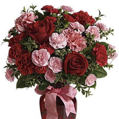 Red roses and pink carnations in a red vase with a pink ribbon