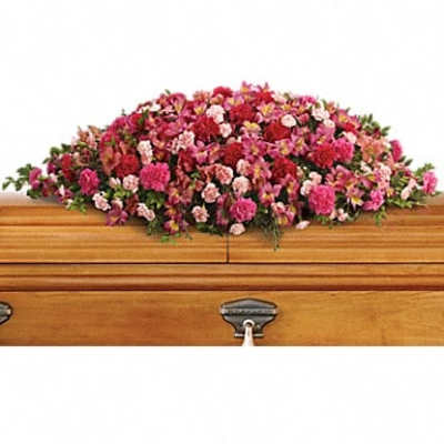 Pink and red floral casket spray on a wooden coffin