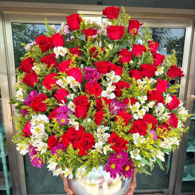 Large bouquet of red roses, white flowers, and purple daisies in a silver vase