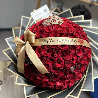 Round bouquet of red roses with a gold ribbon and tiara