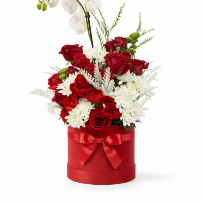 Red roses and white flowers in a red hat box with a white orchid stem