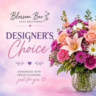 Mixed pink and purple flowers in a glass vase with a designer choice label