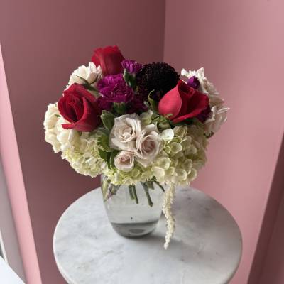 Bouquet of red roses, white hydrangeas, and purple carnations in a glass vase