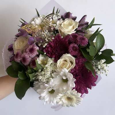 Handheld bouquet of white, purple, and pink flowers with a butterfly pick