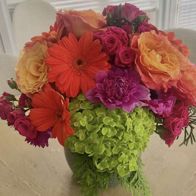 Bright mixed bouquet with roses, gerbera daisies, and green hydrangea in a vase