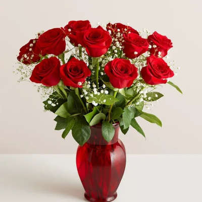 Red roses arranged in a red glass vase with baby's breath