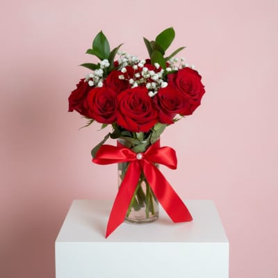 Red roses in a glass vase with a red ribbon bow