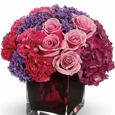 Pink roses and purple flowers arranged in a square glass vase