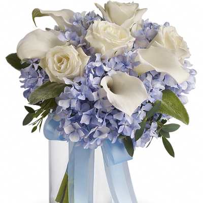 White roses and blue hydrangeas in a glass vase with a blue ribbon