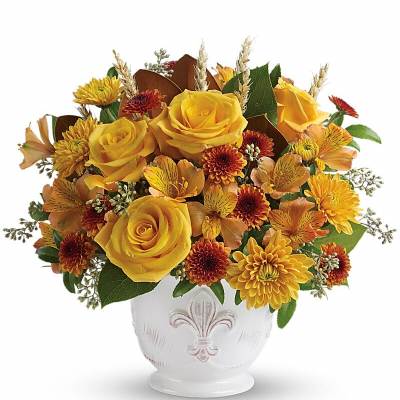 Yellow roses and autumn flowers arranged in a white vase