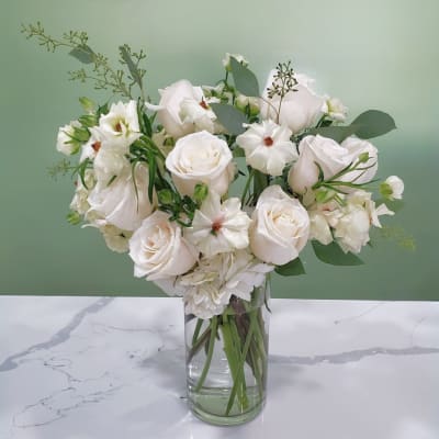 White roses and small white blooms in a clear glass vase