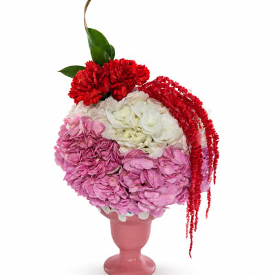 Pink and white floral arrangement in a pink vase with red accents