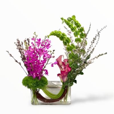 Pink orchids and calla lilies in a clear rectangular vase