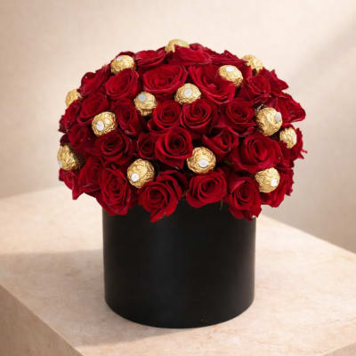 Red roses and gold-wrapped chocolates arranged in a black round box