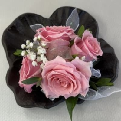 Pink roses arranged in a black wrap with small white filler flowers