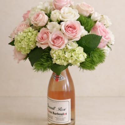 Pink and white roses arranged in a wine bottle vase
