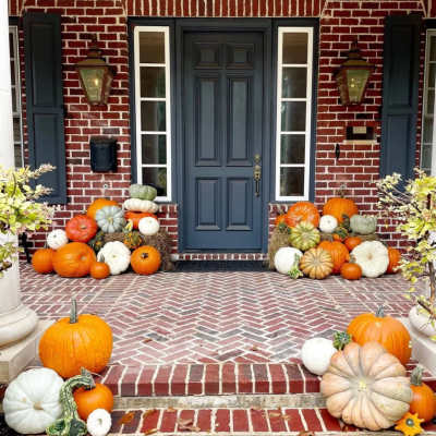 Front porch decorated with pumpkins and gourds around a blue door
