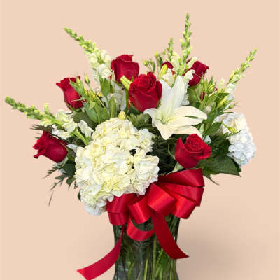 Red roses and white lilies in a glass vase with a red ribbon