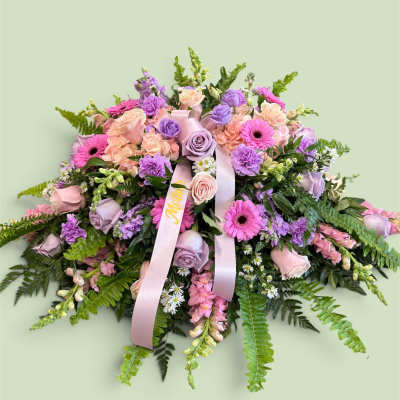 Pink and lavender floral arrangement with ribbon on a pale green background