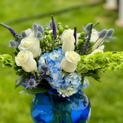 Blue and white floral arrangement in a cobalt glass vase