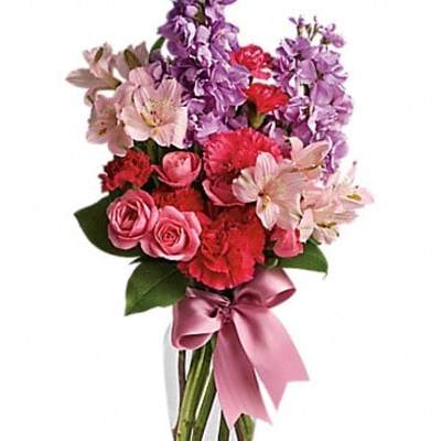 Pink and purple mixed bouquet in a clear glass vase with a satin ribbon