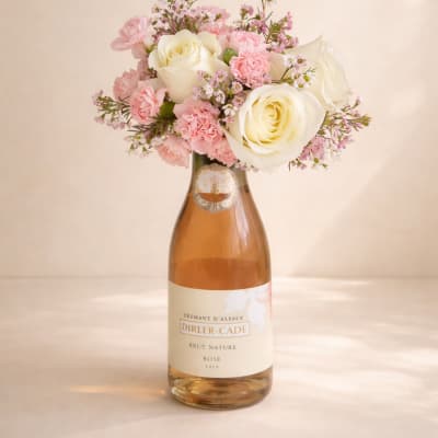 Pink and white flower arrangement in a champagne bottle vase