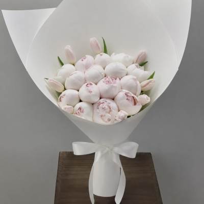 Bouquet of pale pink peonies and tulips wrapped in white paper