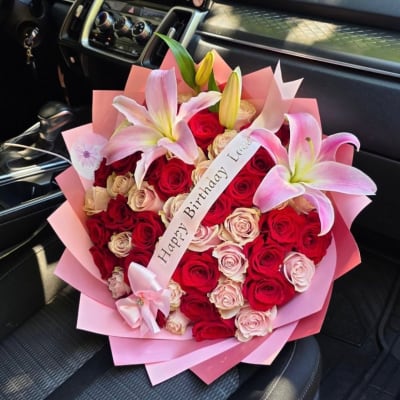 Bouquet of red and blush roses with pink lilies and a birthday ribbon