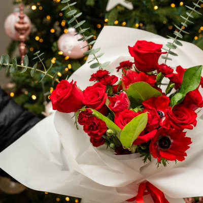 Bouquet of red roses and red anemones wrapped in white paper