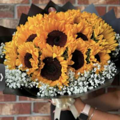 Bouquet of orange sunflowers with white baby's breath in black wrap