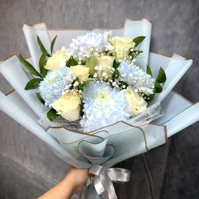 Bouquet of pale blue chrysanthemums and cream roses wrapped in light blue paper
