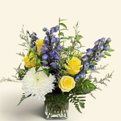 Yellow roses and white chrysanthemum in a glass vase with blue flowers