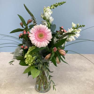 Pink gerbera daisy arrangement in a clear glass vase with white blooms