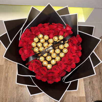 Heart-shaped bouquet of red roses with gold-wrapped chocolates and a black ribbon