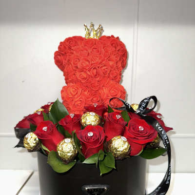 Red rose arrangement in a black round box with a small crown topper