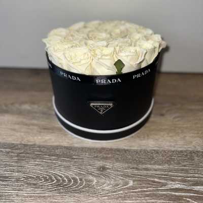 Cream roses arranged in a black round box with Prada branding