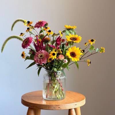 Mixed bouquet of yellow and pink flowers in a clear glass vase