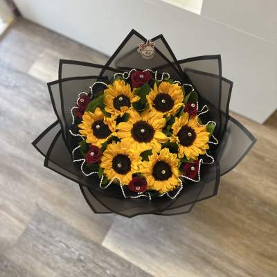Bouquet of sunflowers and red roses wrapped in black paper
