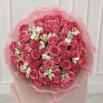 Bouquet of pink roses and white alstroemeria wrapped in pink tissue