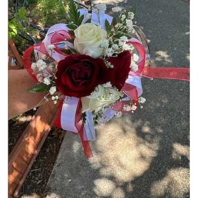 Red and white rose corsage with baby's breath and red and white ribbon on a wrist