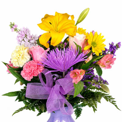 Colorful bouquet with lilies, roses, and daisies in a purple vase