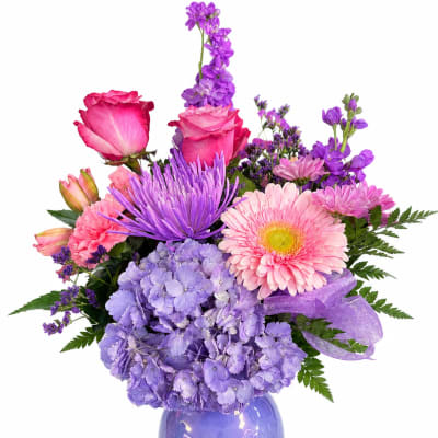 Purple and pink mixed flower arrangement in a purple vase