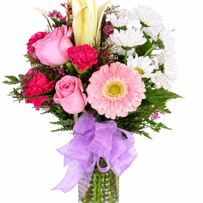 Pink and white mixed bouquet in a glass vase with a purple ribbon