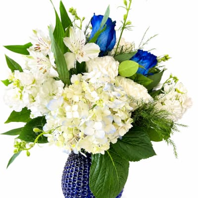 White and blue floral arrangement in a cobalt blue vase
