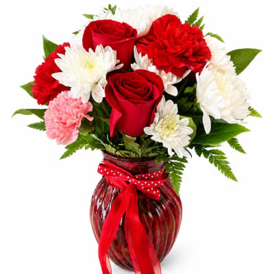 Red roses and white chrysanthemums in a red glass vase with a ribbon