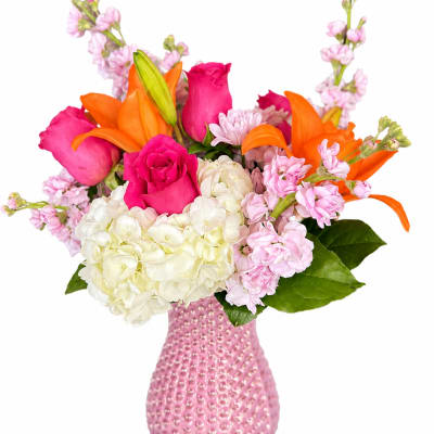 Pink and orange bouquet with roses, lilies, hydrangea, and a pink vase