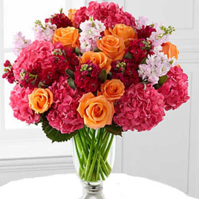 Bouquet of orange roses and pink hydrangeas in a clear glass vase